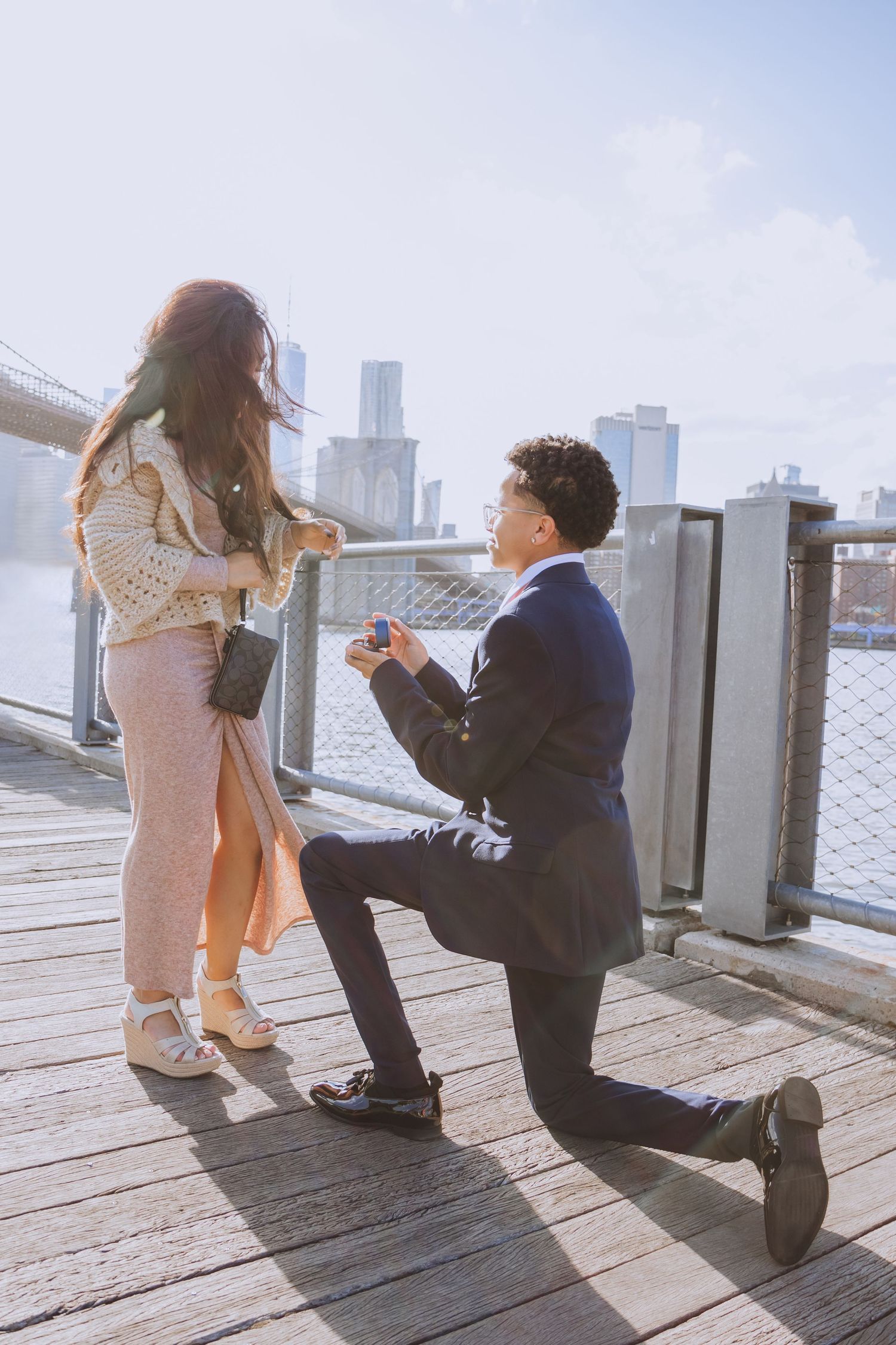 A surprise marriage proposal on a waterfront deck with city skyscrapers in view.