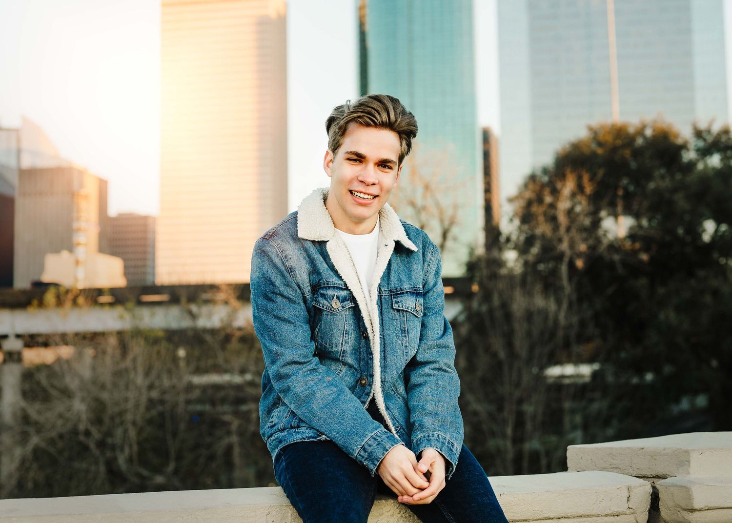 Natural light portrait session with person in denim jacket against city skyline.