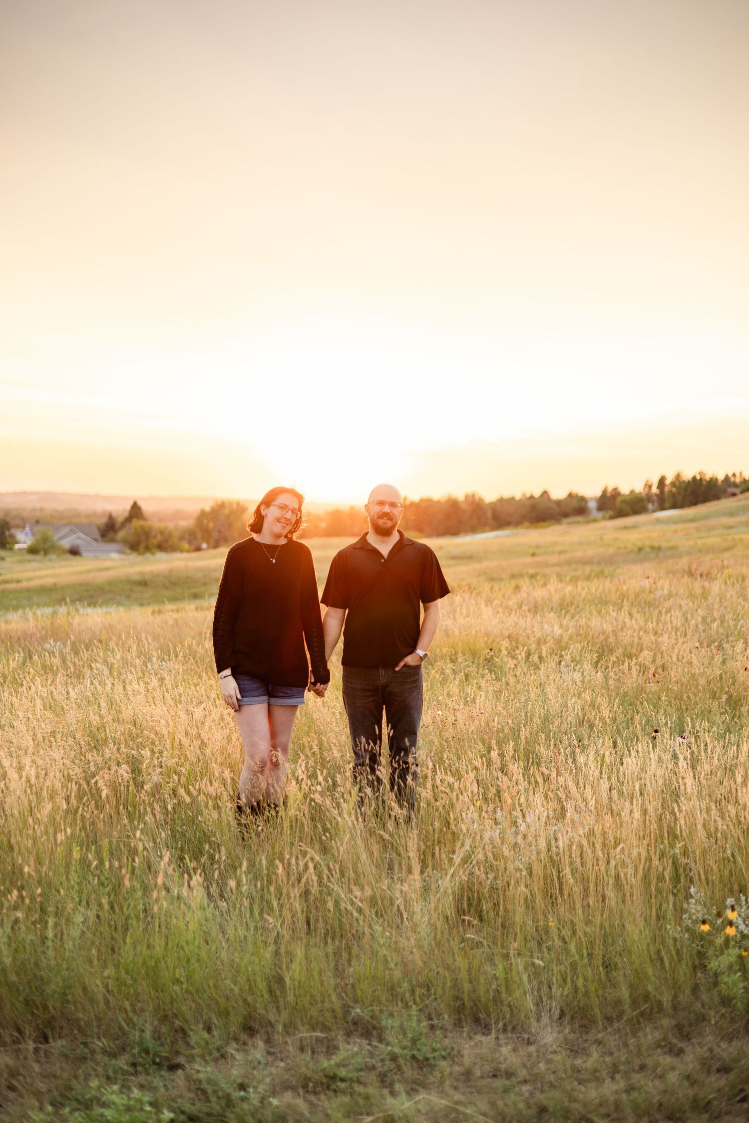 A couple shares a peaceful moment in a grassy field during golden hour.