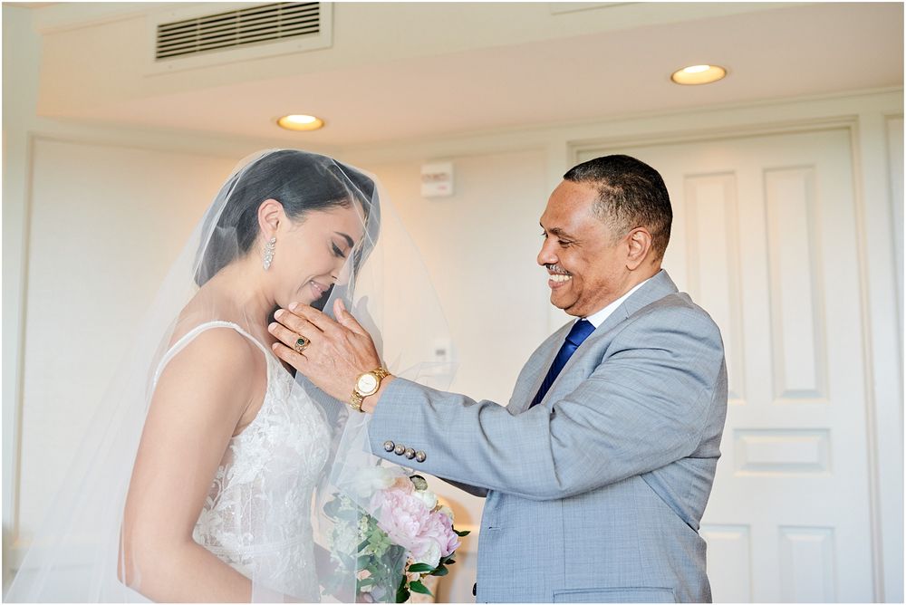 An emotional first look moment between a bride in white and someone wearing a light gray suit.