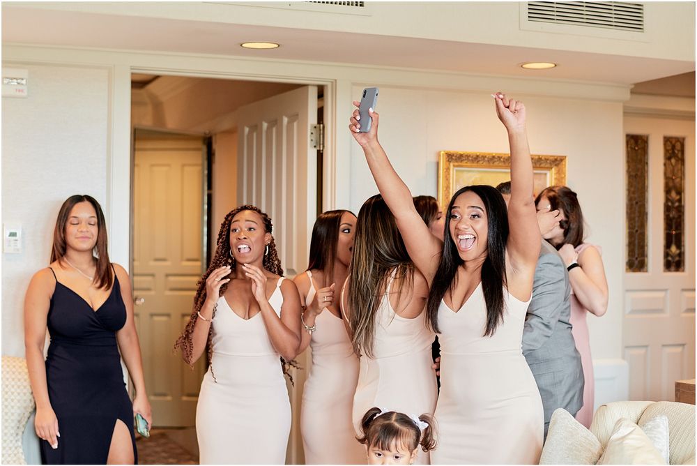 Bridesmaids in matching dresses share a candid moment of laughter in an elegant room.