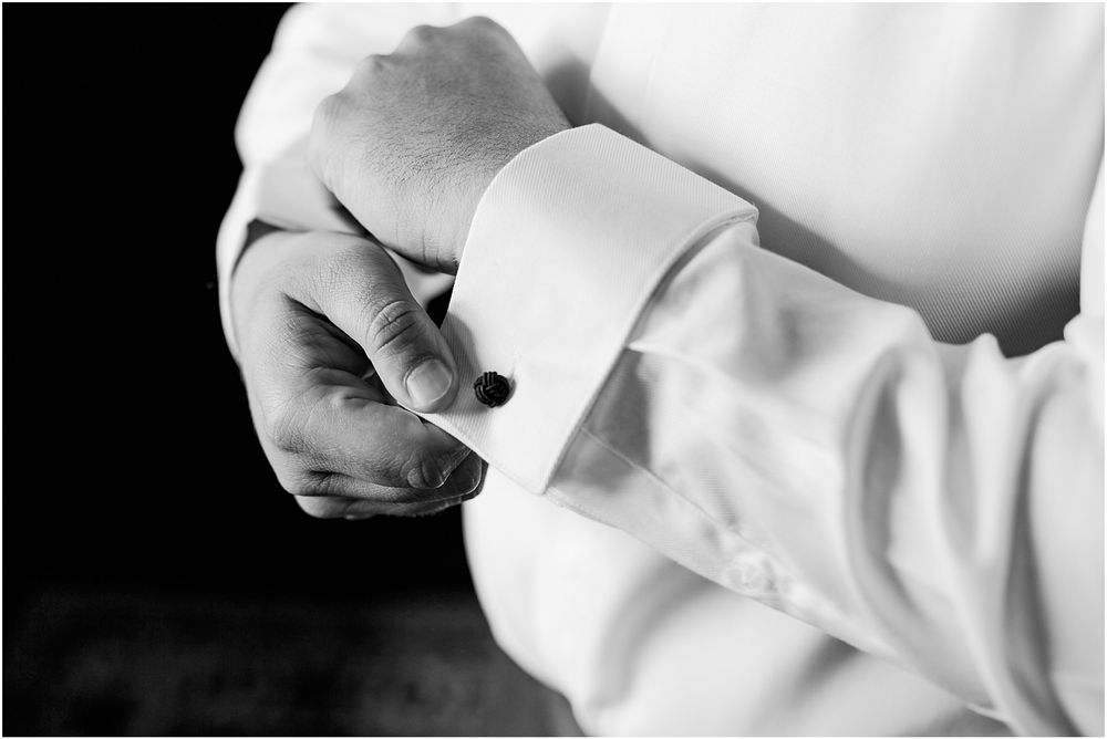 Close-up black and white photo of hands adjusting white dress shirt cuffs.