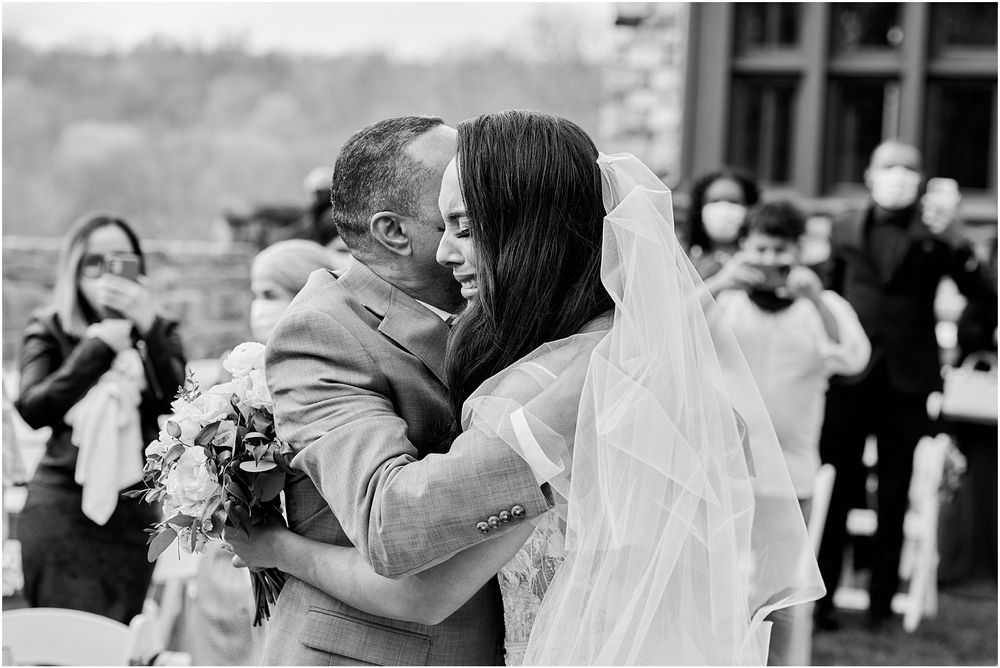 Black and white candid moment during outdoor wedding ceremony with stone backdrop.