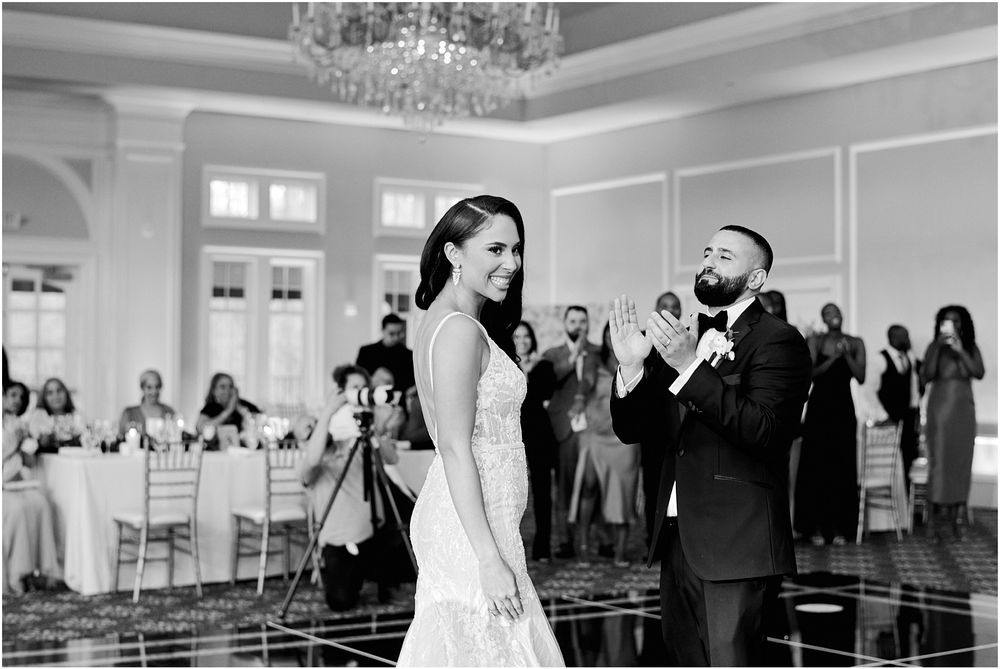 Elegant ballroom wedding scene with chandelier and classic architectural details.