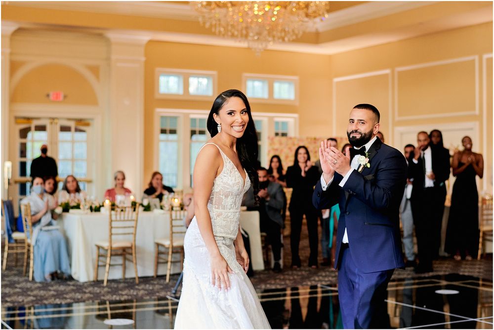 Wedding reception dance in elegant ballroom with cream walls and reflective floor.
