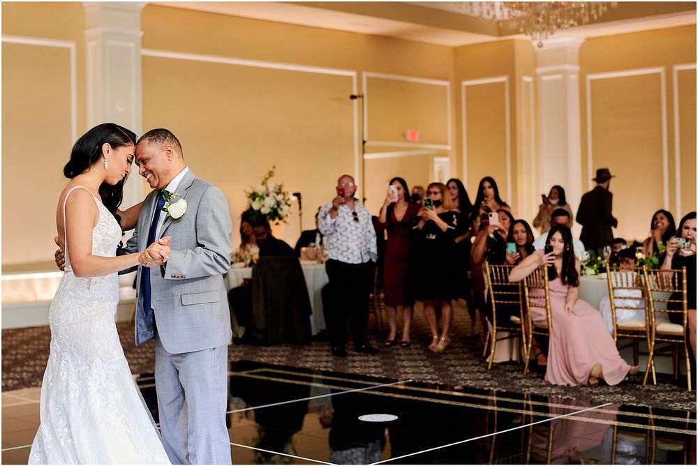 Intimate dance moment shared during wedding reception with guests looking on.