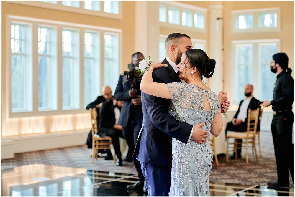 A touching dance moment captured in a bright ballroom with large windows and elegant decor.