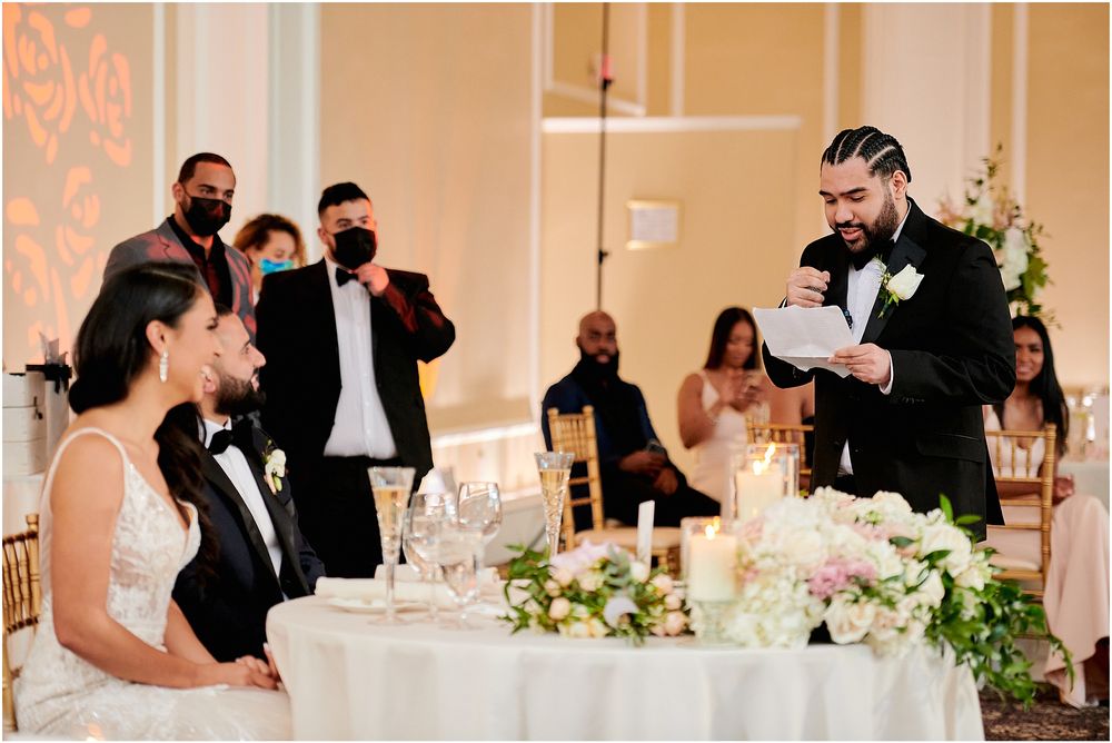 Wedding reception toast moment at an elegant venue with beautiful table settings and floral centerpieces.