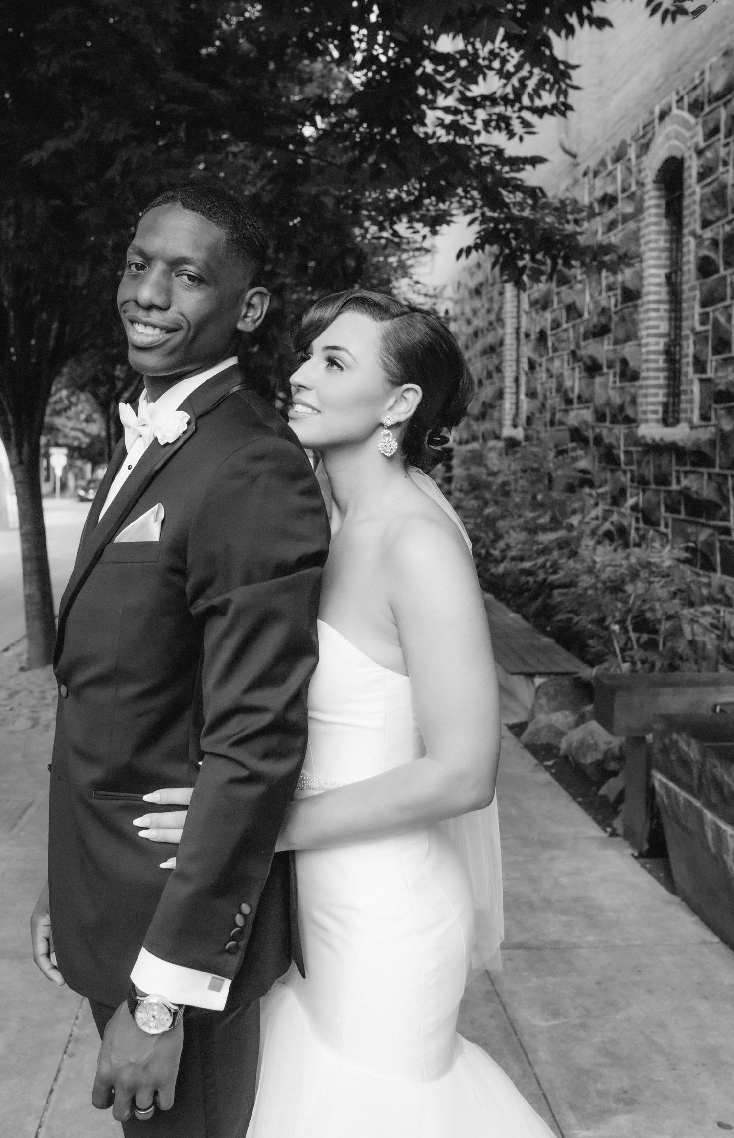 Black and white wedding portrait of couple in formal attire outdoors.