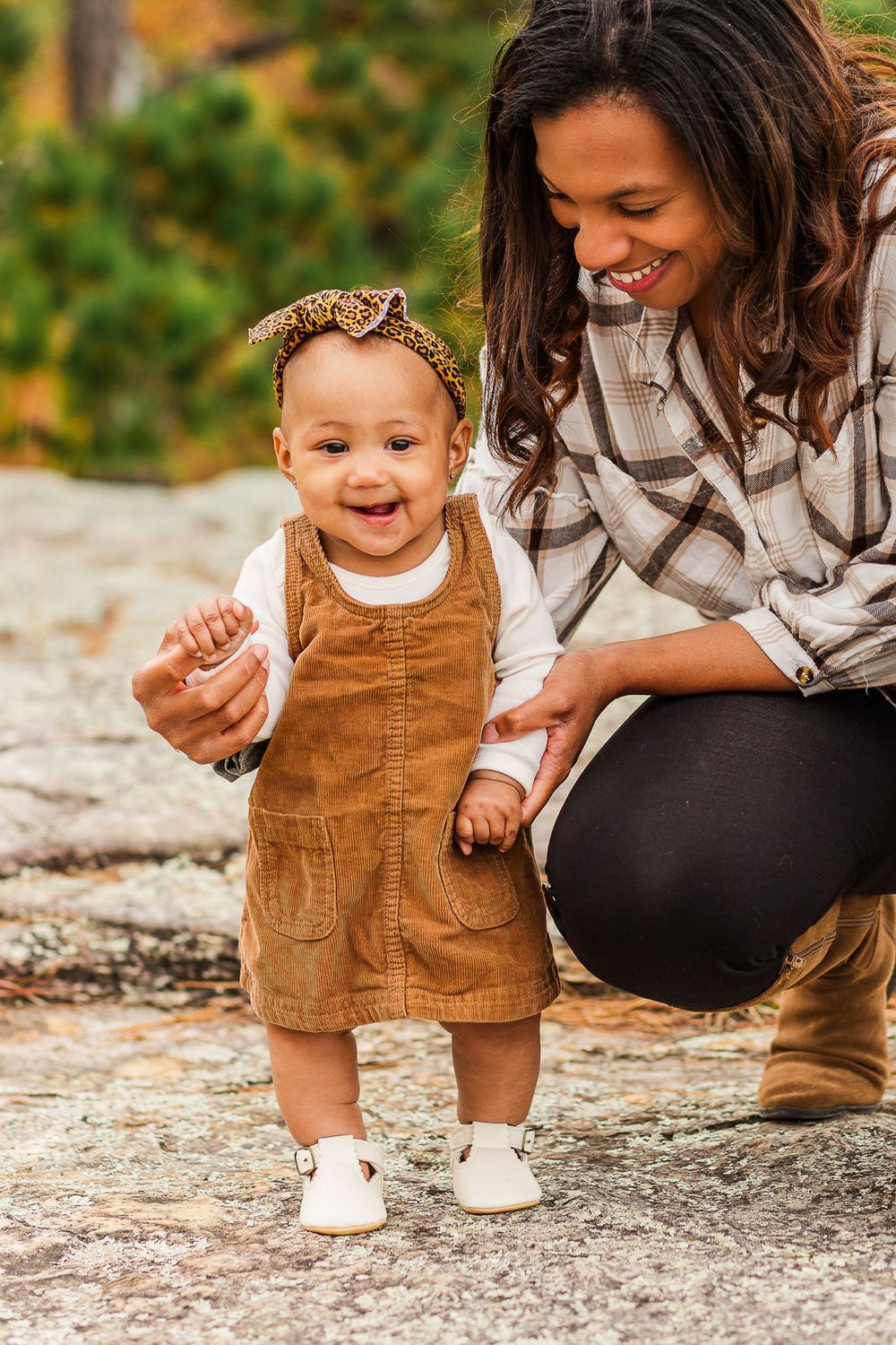Sweet moment between parent and toddler in corduroy dress during outdoor photoshoot.