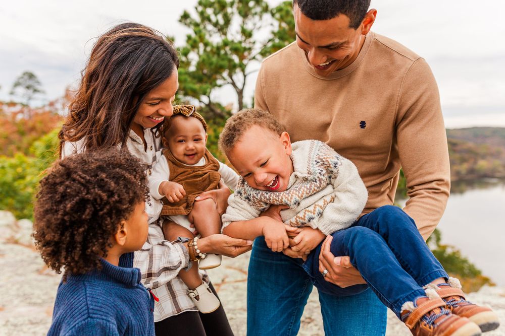 Joyful family laughing together during outdoor photo session.
