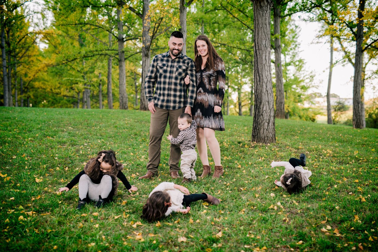 Family portrait in a park with their three border collie dogs lying in the grass.
