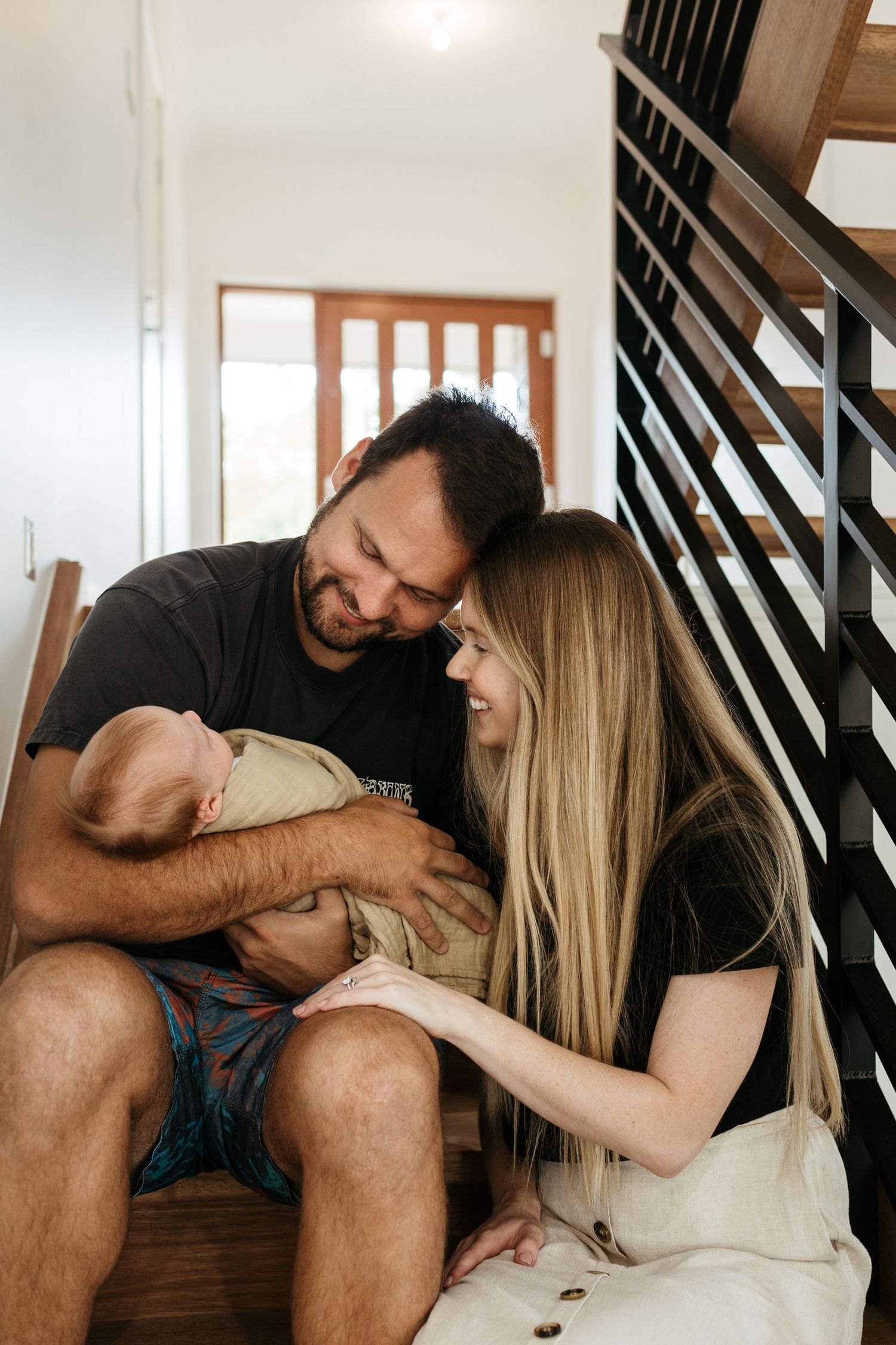 Mother, father and newborn baby sitting on the stairwell of their home