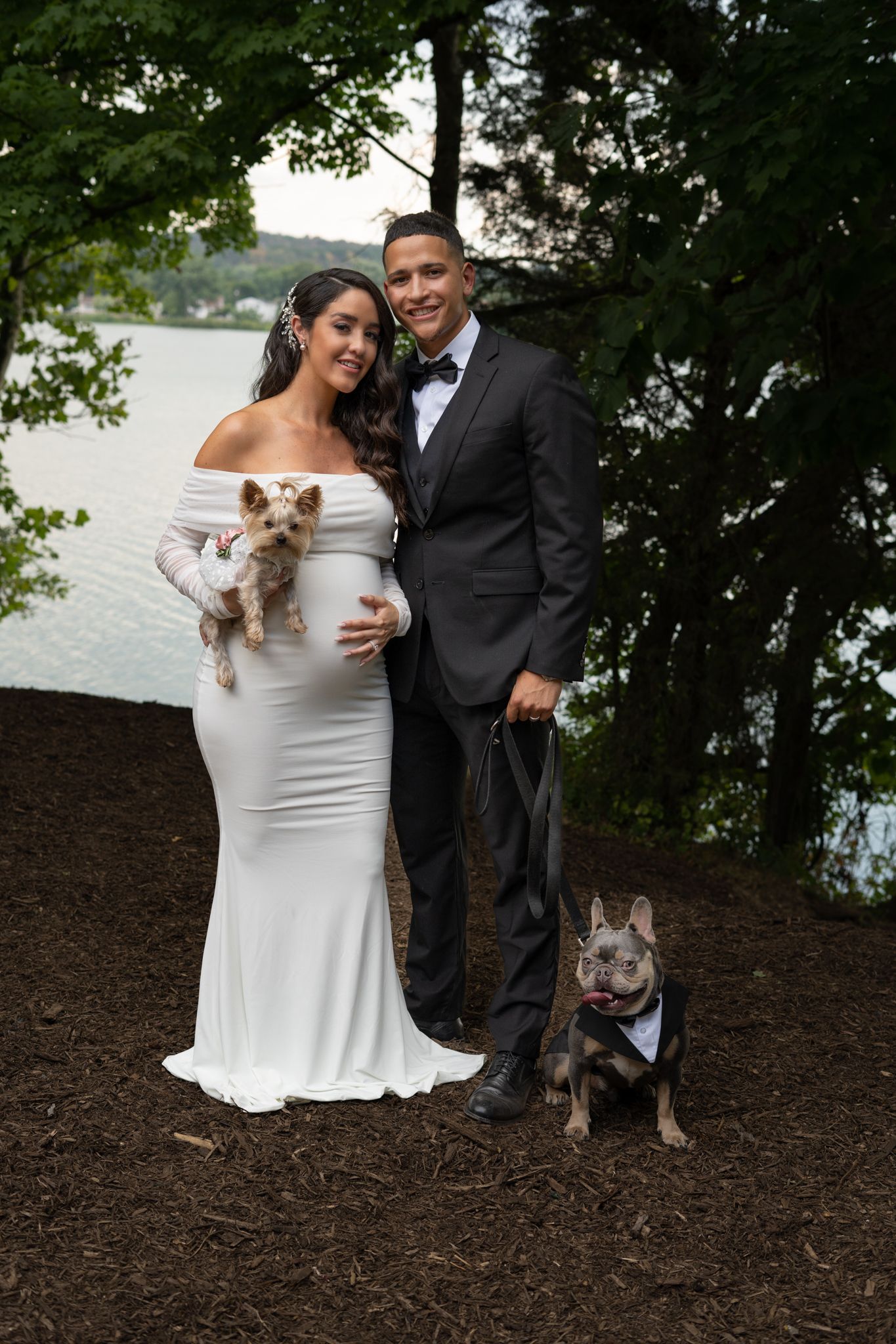 Outdoor wedding photography featuring couple with their dog in natural wooded setting.