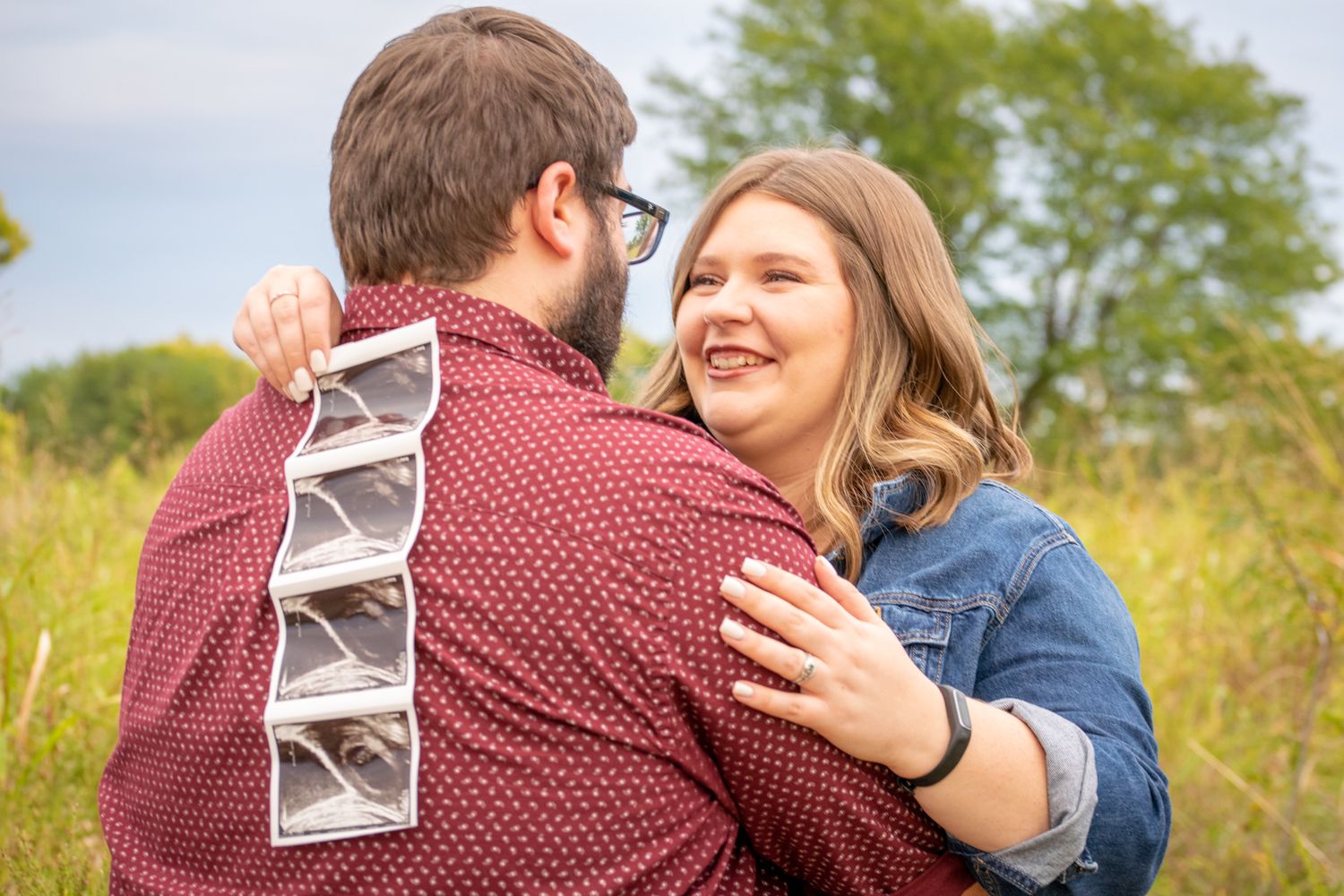 A couple smiles at each other. Mom is holding ultrasound photos. Baby announcement session. Kansas City MO