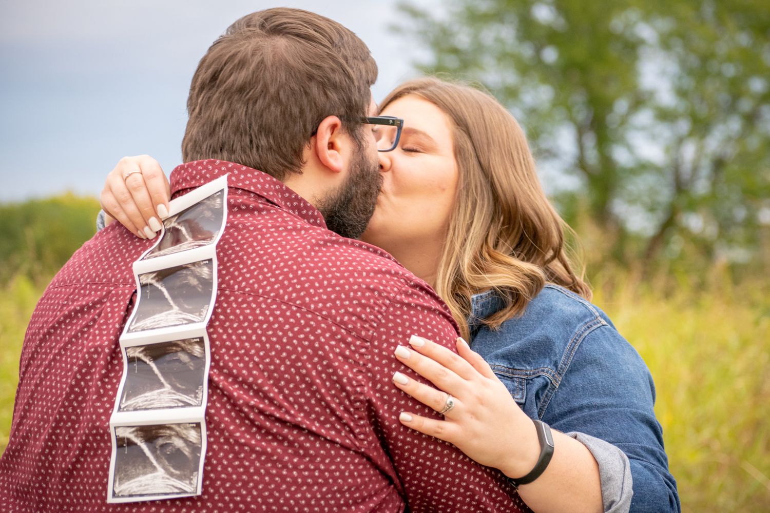 A couple kisses. Mom is holding ultrasound photos. Baby announcement session. Kansas City MO