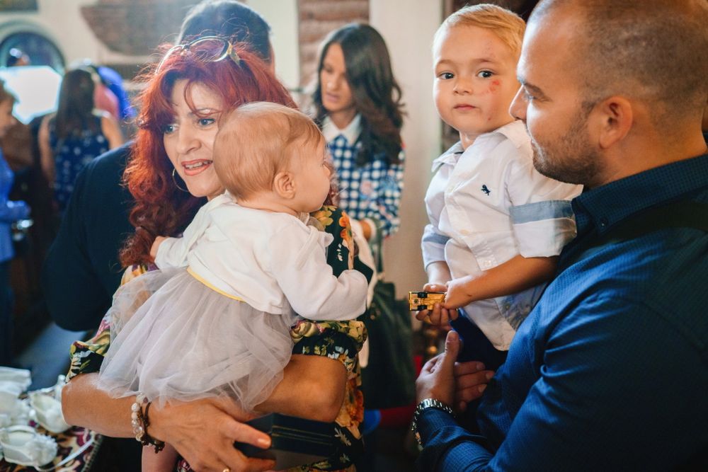 Group of people gathered indoors holding babies at a social event.