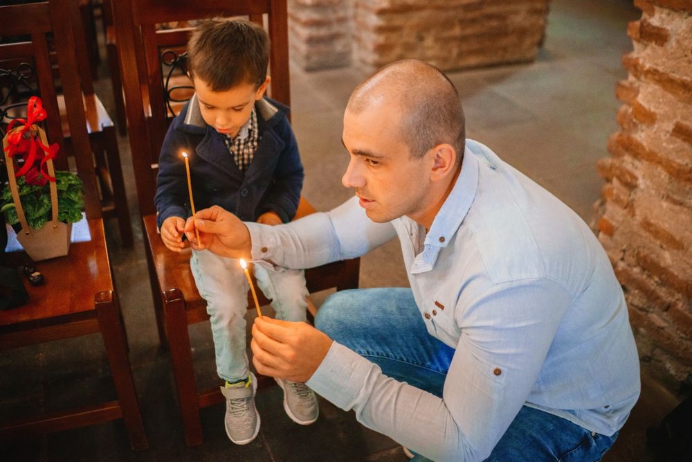 Two people examining something near wooden furniture in a brick interior space.