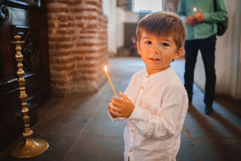 Young child in white shirt holding something in a church interior with brick walls.