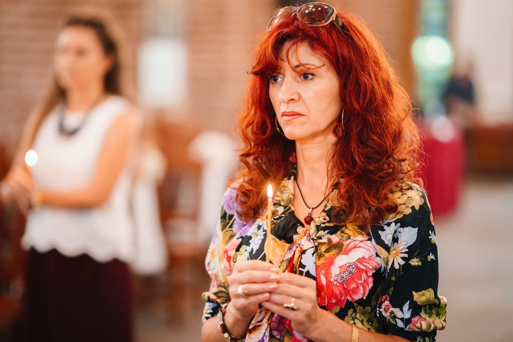Woman in floral print top attending ceremony in brick church interior.