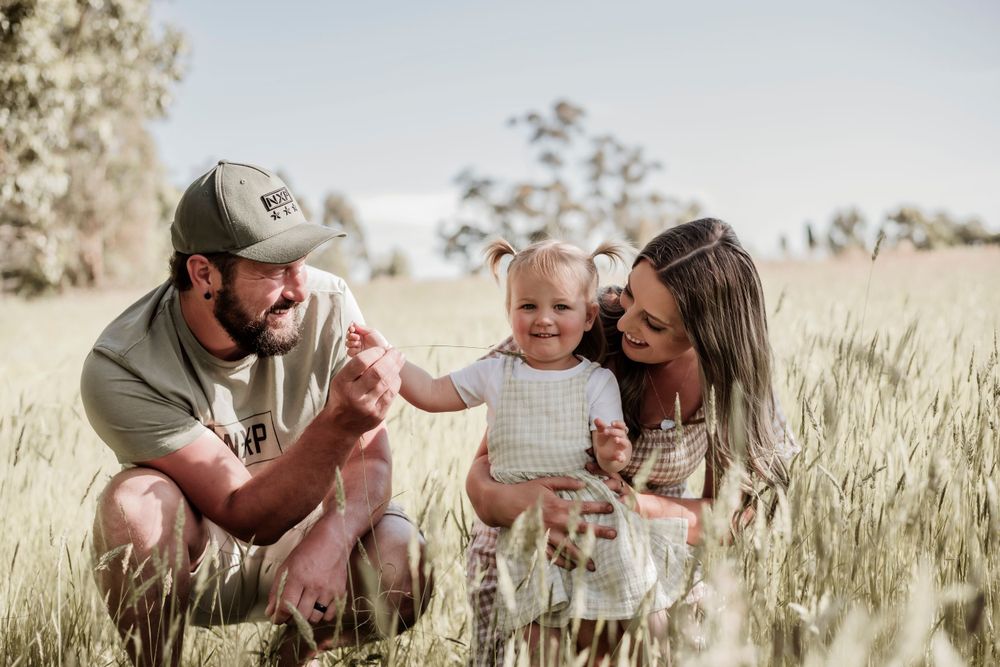 A family sits together in a golden wheat field on a sunny afternoon.