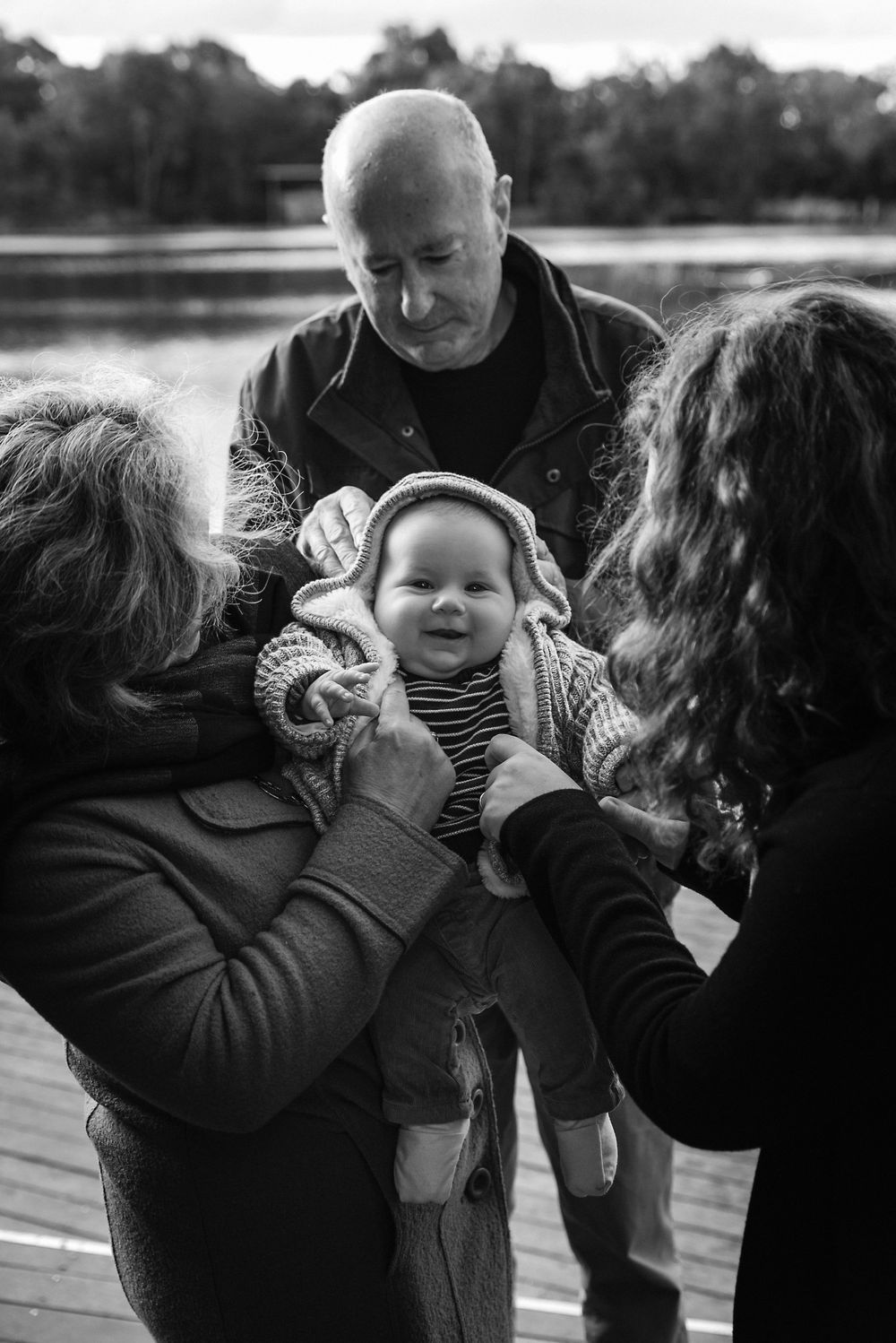A heartwarming black and white photo of a family moment together on a dock by a lake.