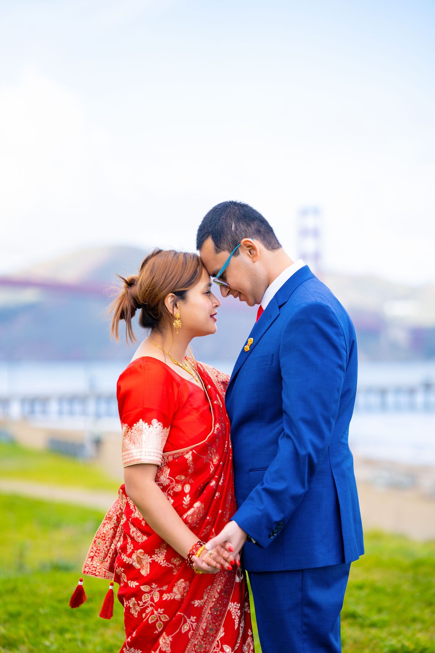 A tender moment between a couple in traditional dress with the Golden Gate Bridge visible in the distance.