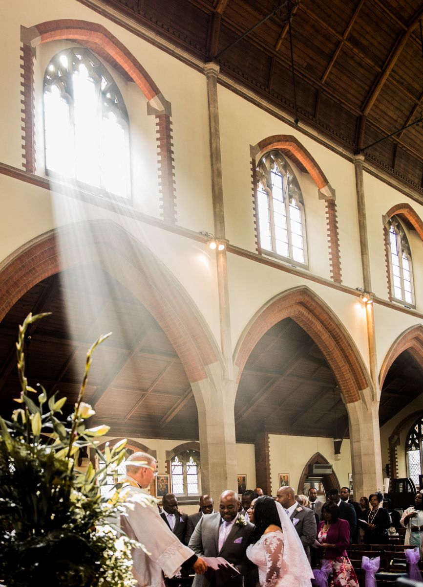 Sunbeams stream through church windows during a wedding ceremony.