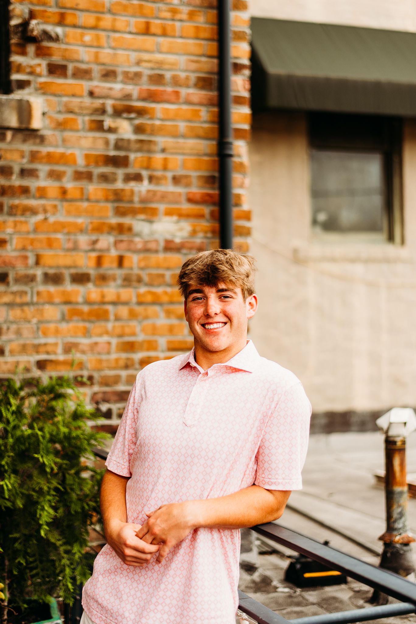 Casual outdoor portrait against a brick wall with natural lighting.