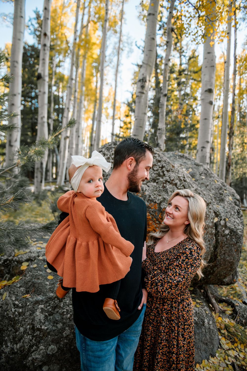 Candid family moment captured in golden aspen forest during autumn.