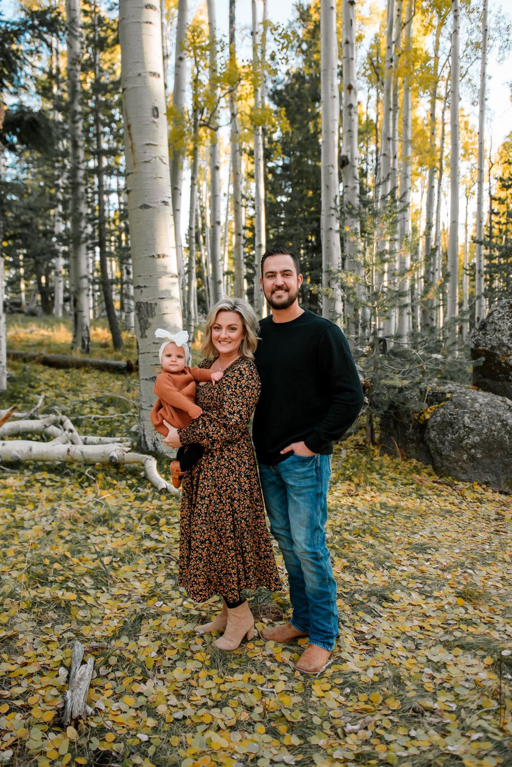 Family photo session in a scenic aspen forest with fall foliage on the ground.