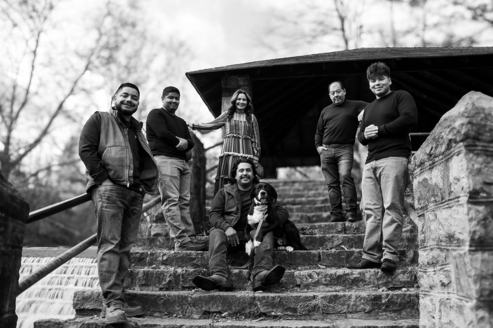 Black and white photo of family group with dog posing on stone steps in outdoor park setting.