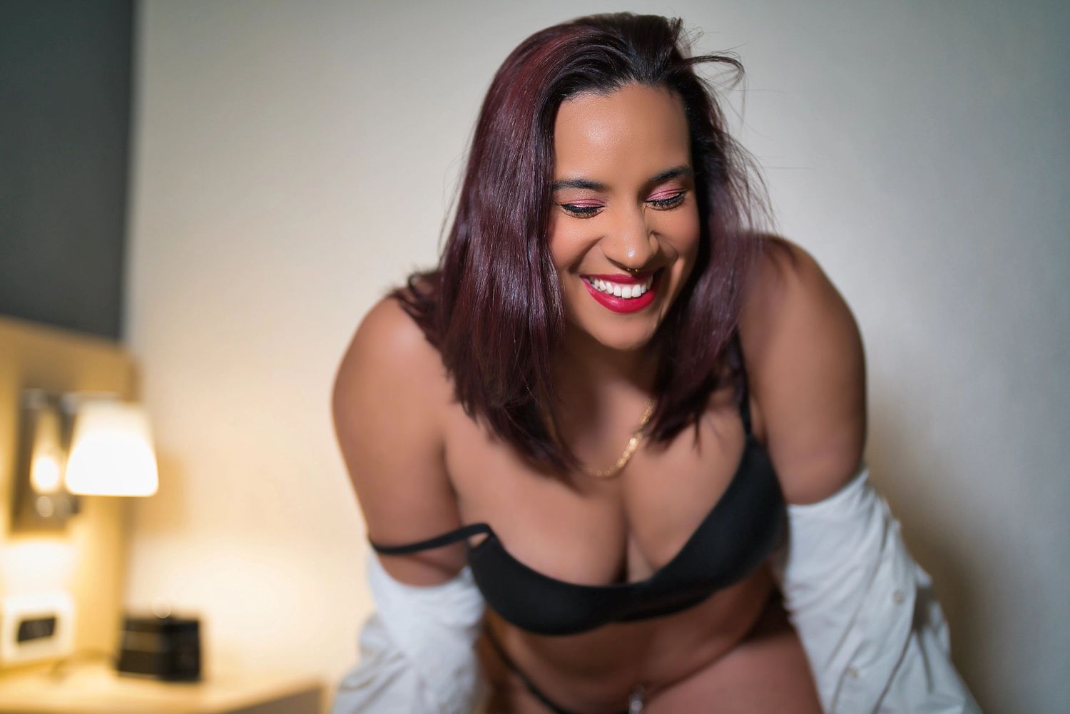 A boudoir photography session featuring intimate poses in a dimly lit bedroom setting.
