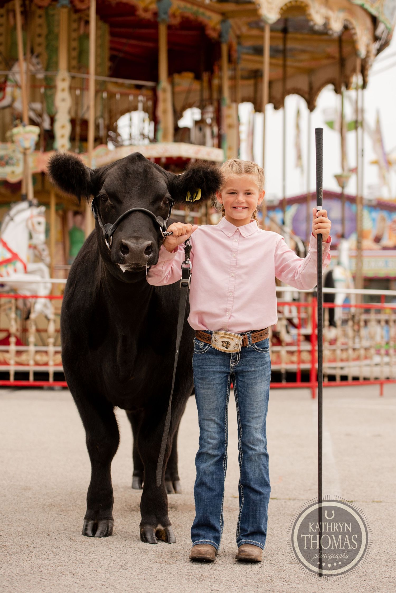 A young exhibitor stands proudly with their black show cow at the county fair.