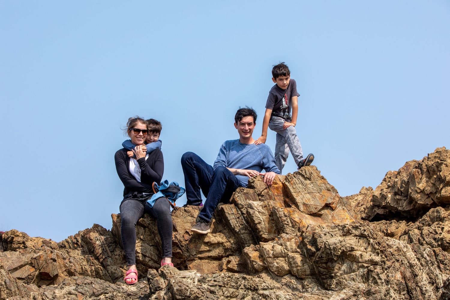 Mendocino Headlands candid family photo on the rocks. J.Perlman Photography previous wedding couple with their 2 children.