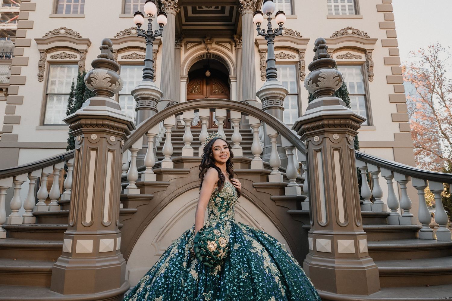 Elegant teal quinceañera dress photographed on grand vintage mansion staircase.