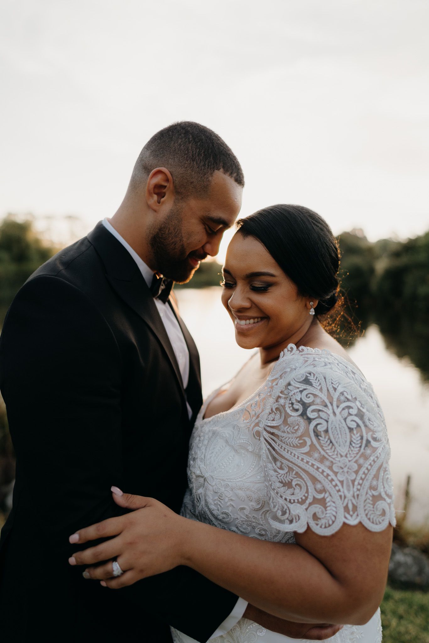 bride and groom hugging at sunset with a lake in the background