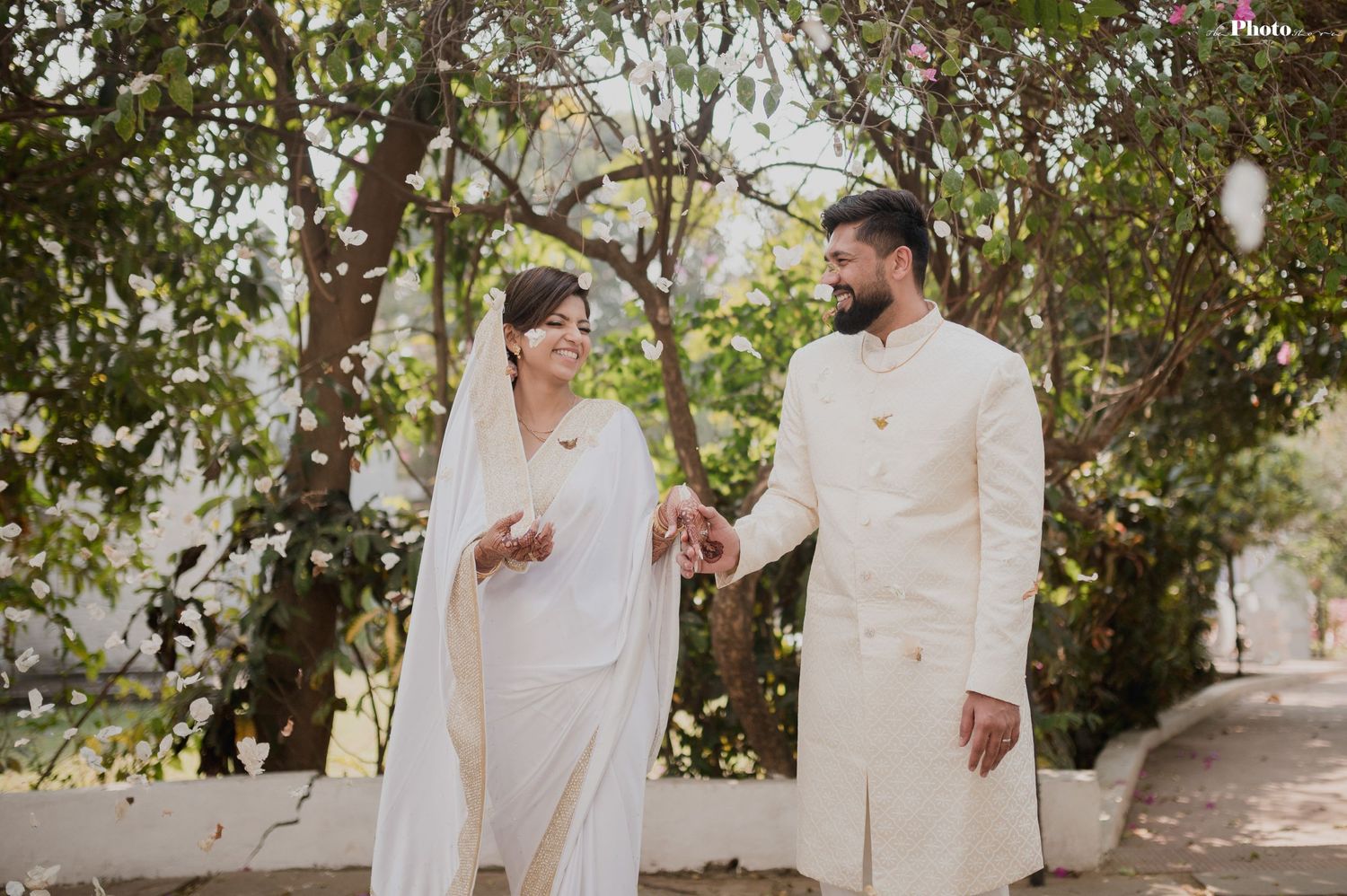 Couple shares a light moment while walking together in white traditional outfits.