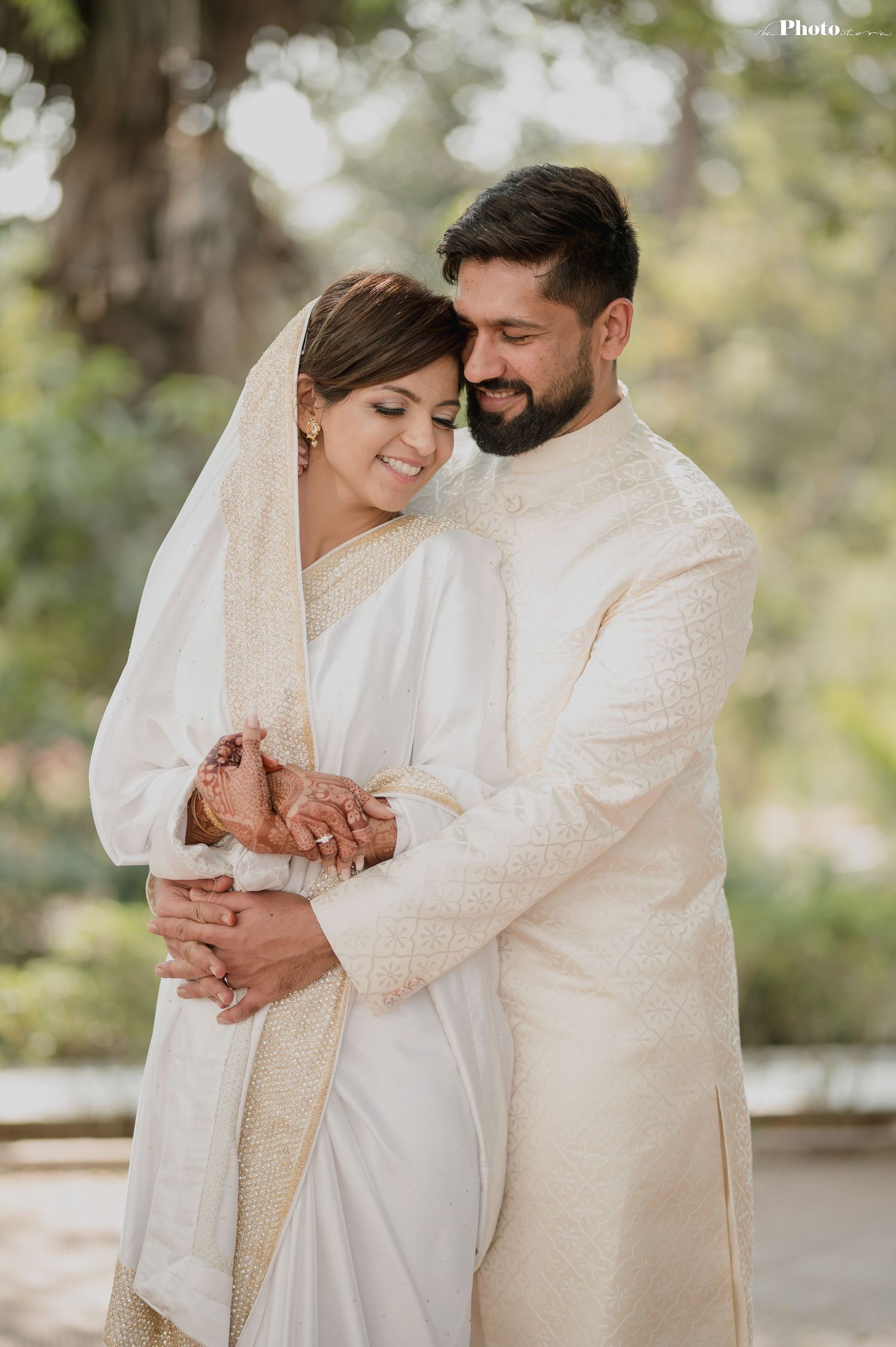 Intimate moment captured between couple in traditional white wedding attire against natural backdrop.