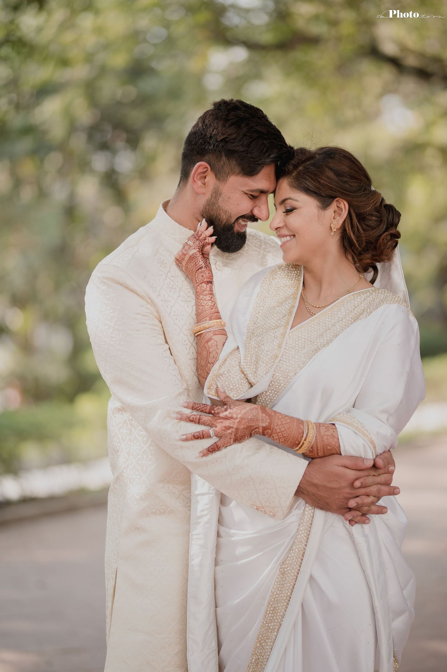 Romantic portrait of couple in white traditional attire with intricate henna details.