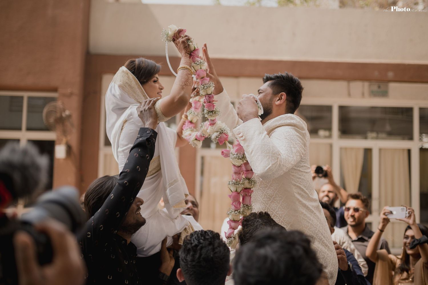 Indoor wedding celebration with guests throwing confetti and dancing.