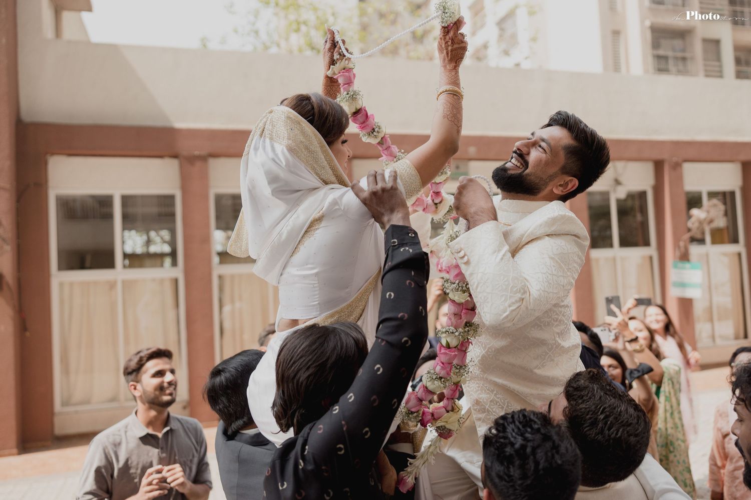 Joyful celebration at an outdoor wedding ceremony with guests tossing flower petals in the air.
