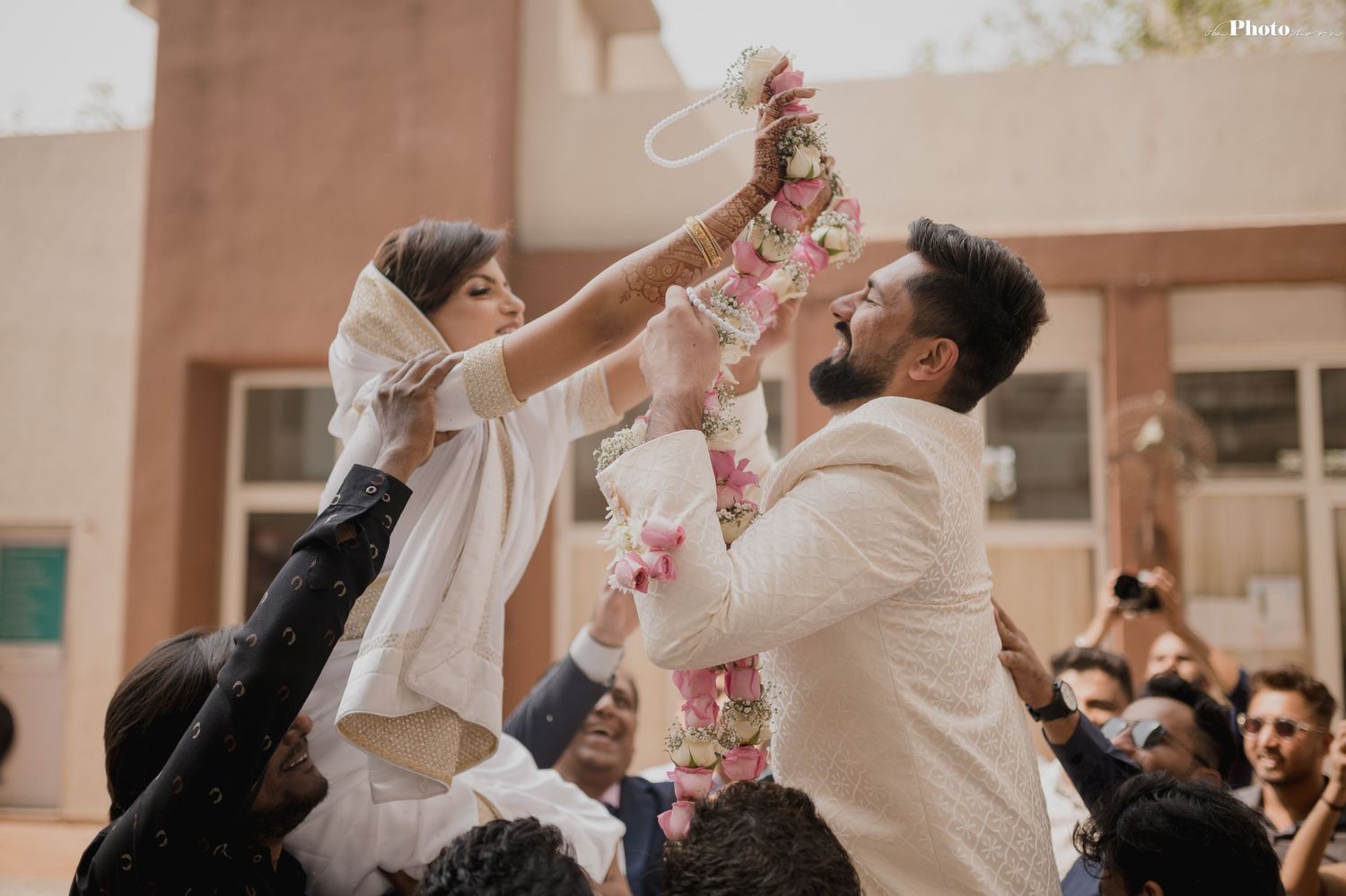Wedding guests showering the newlyweds with pink flower petals during an outdoor celebration.