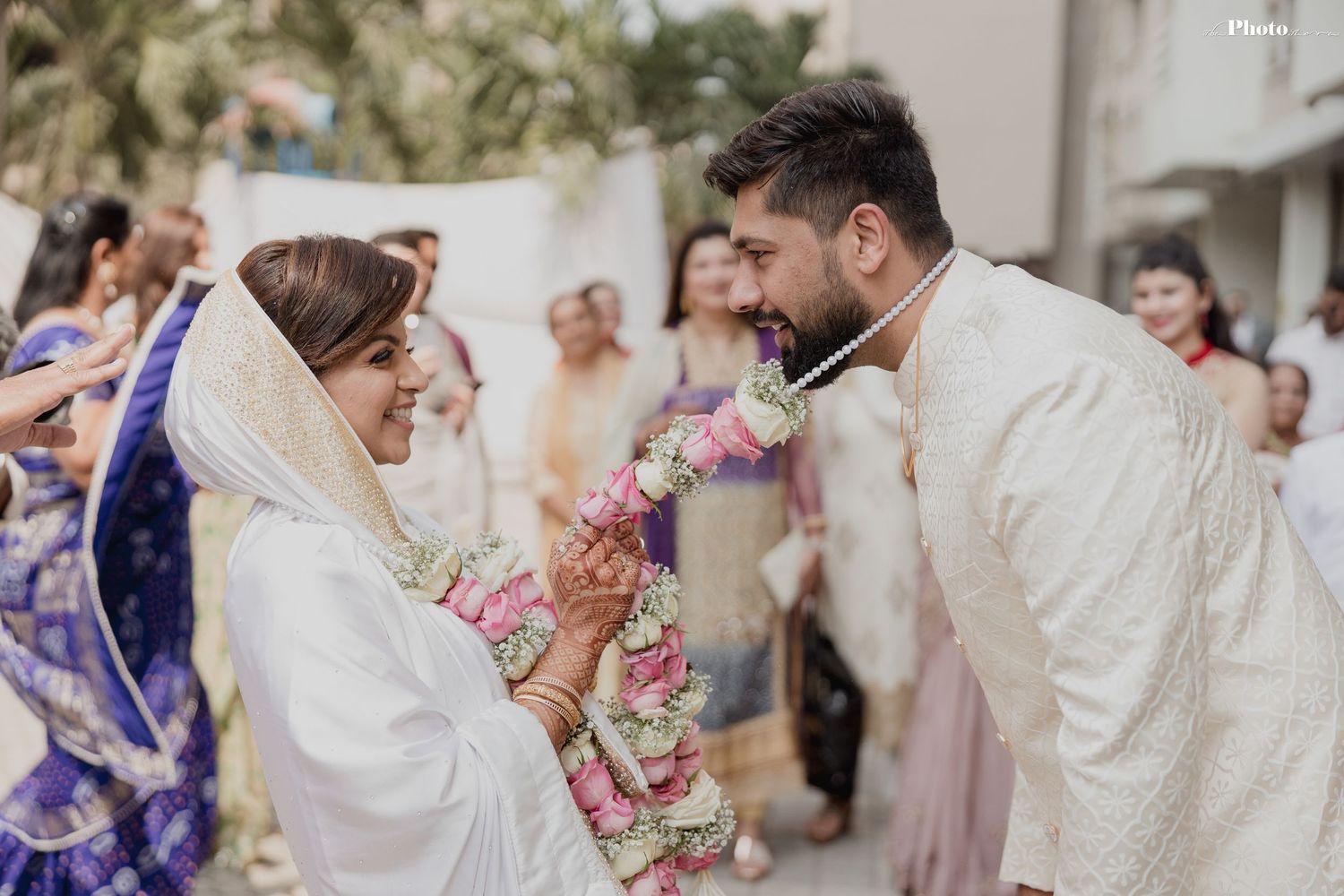 Festive outdoor wedding scene with guests throwing rose petals during a celebration.