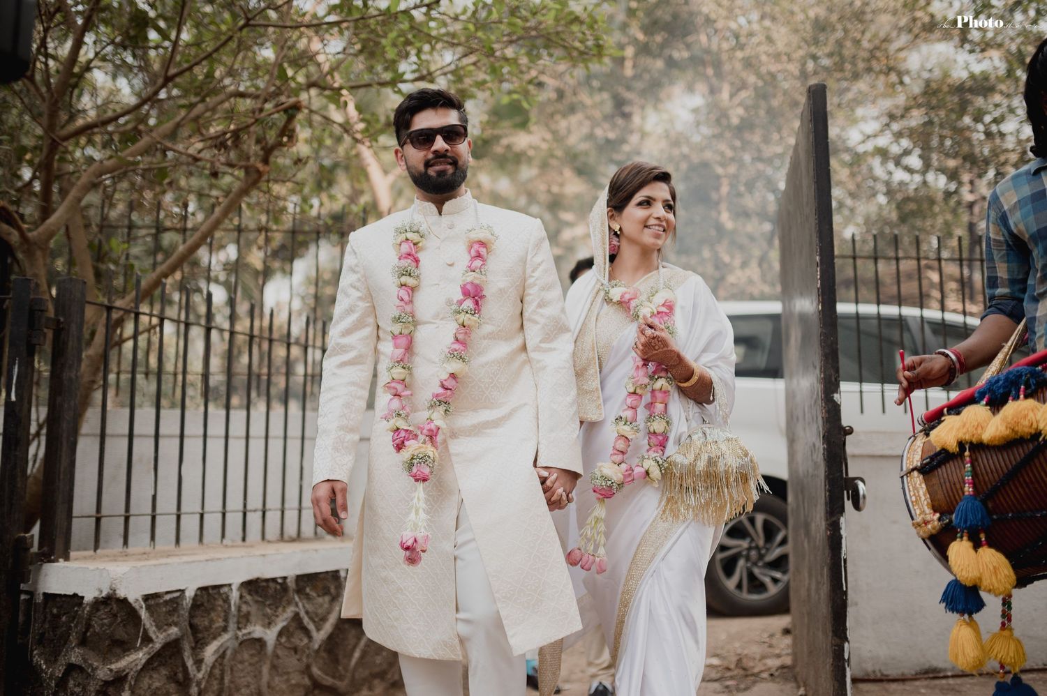 A couple in coordinated white wedding attire shares intimate moments in an outdoor setting.
