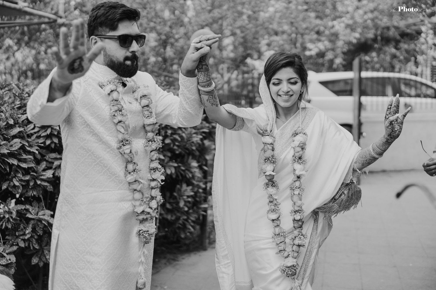 A couple in matching white outfits shares candid moments during their wedding photoshoot.