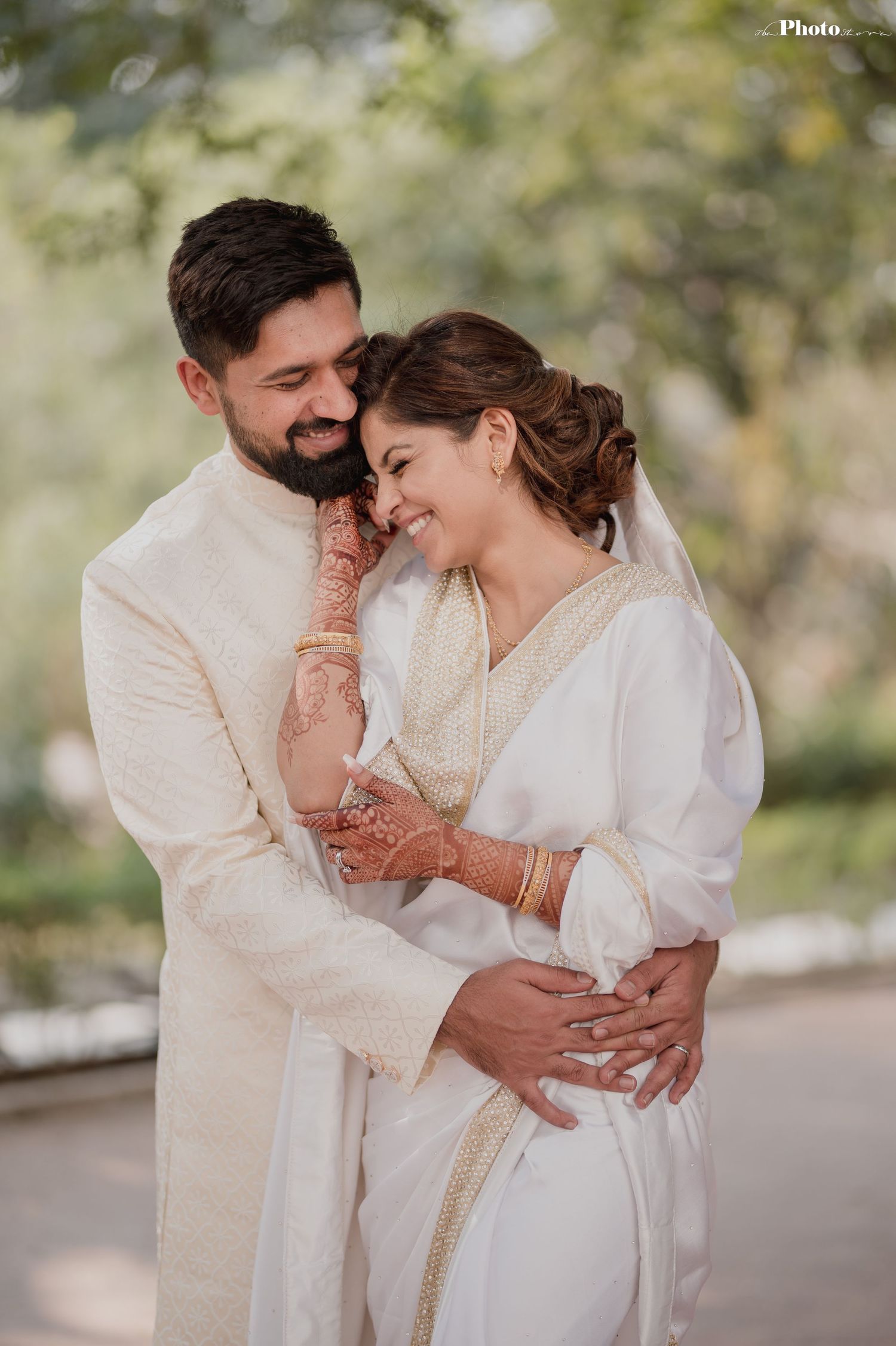A tender moment between newlyweds in white traditional attire with intricate henna details.