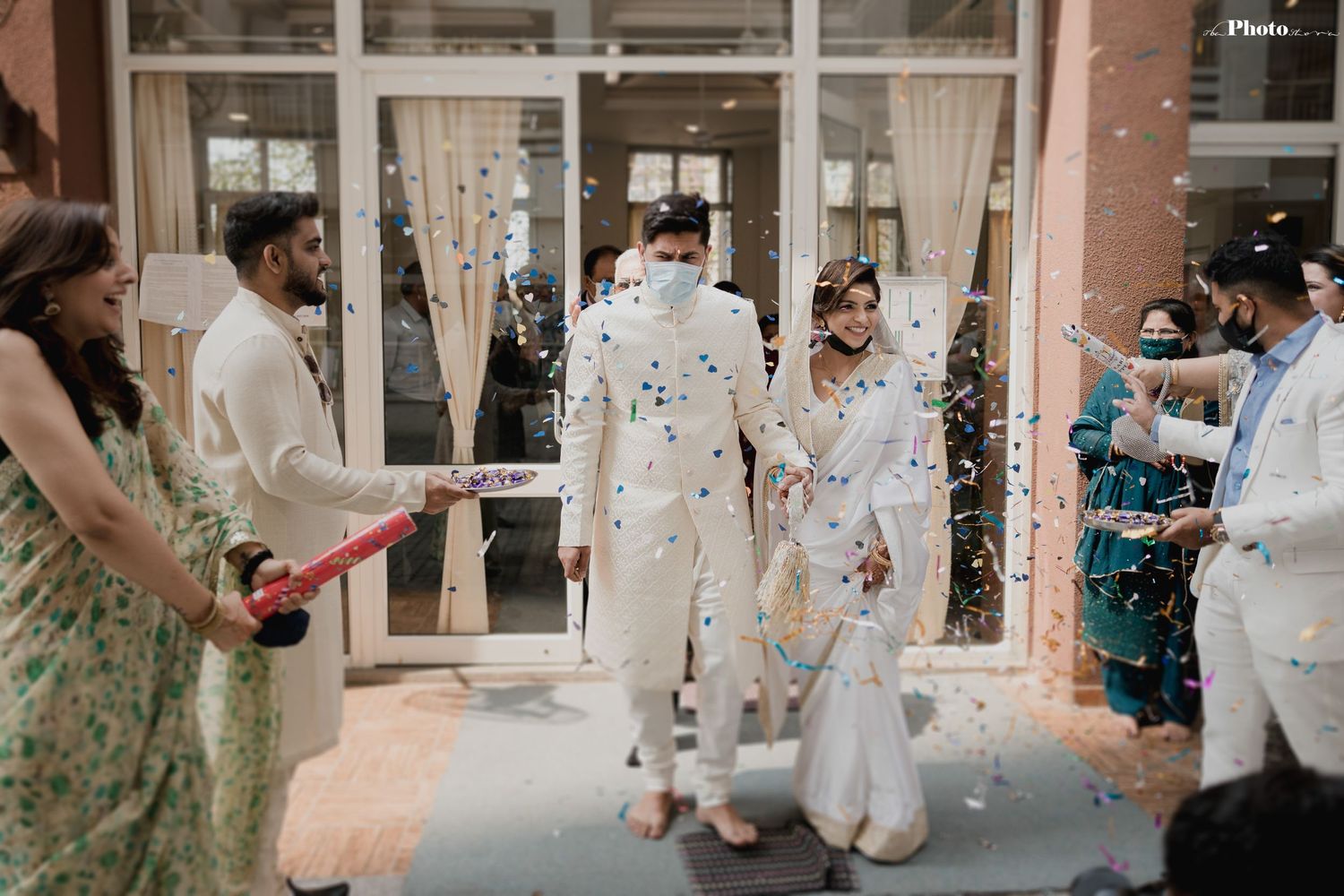 Wedding celebration outside building with guests throwing confetti.