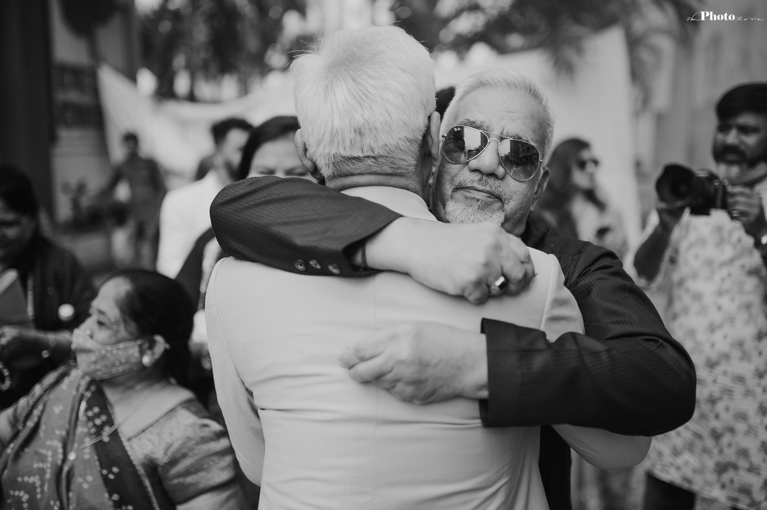 Black and white photo of guests embracing during an emotional wedding celebration.
