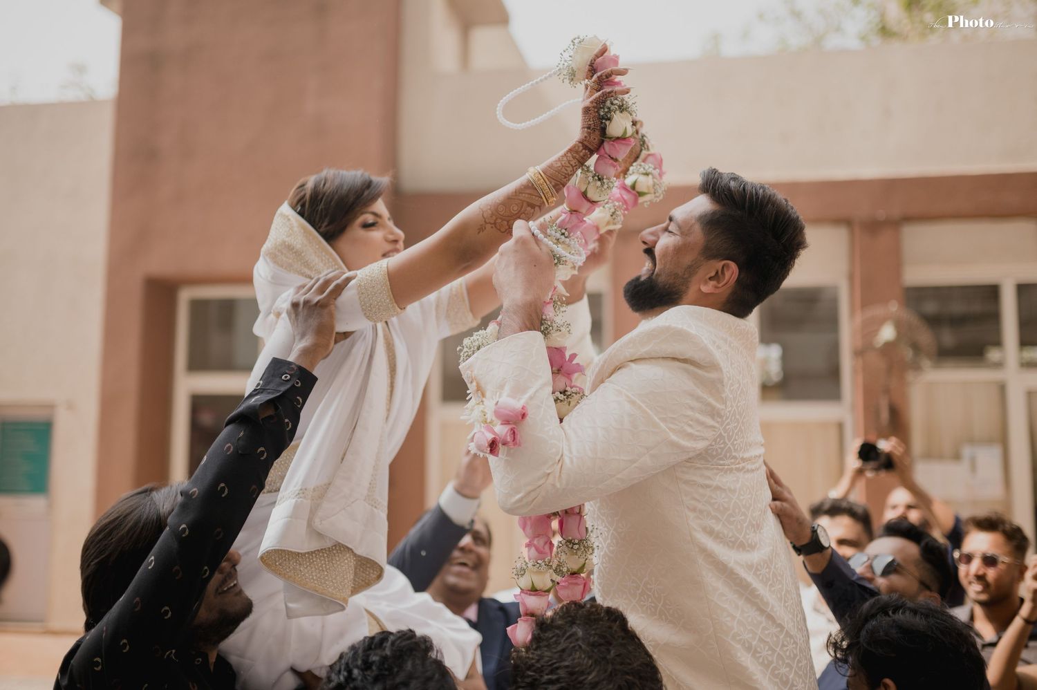 Outdoor celebration with guests throwing rose petals in warm sunlight.